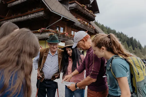 Wandergruppe mit Wanderkarte steht vor dem Moasterhaus und berät sich zur bevorstehenden Wandertour.