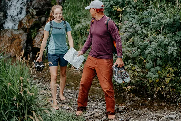 Frau und Mann Wandern entlang des Weges - dahinter einer kleiner Wasserfall.