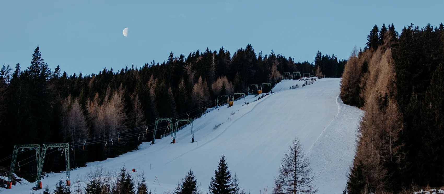 Blick auf die frisch präparierte Piste - abendlicher Himmel mit Halbmond